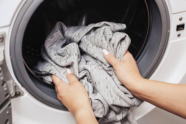 istock Putting clothes into washer. Woman holding grey laundry. Household work routine. 2220094079