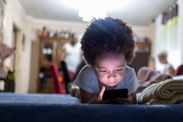 istock Toddler boy laying in bed using smartphone. 2220094960