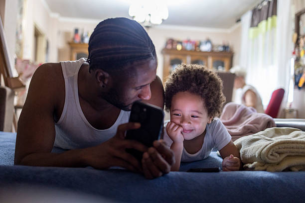 istock Father & son laying in bed looking at smartphone screen. 2220094962