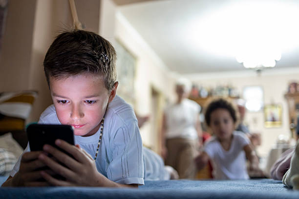istock Young Friends at Play – One Boy Watching Smartphone While the Other Runs Toward the Bed. 2220095929