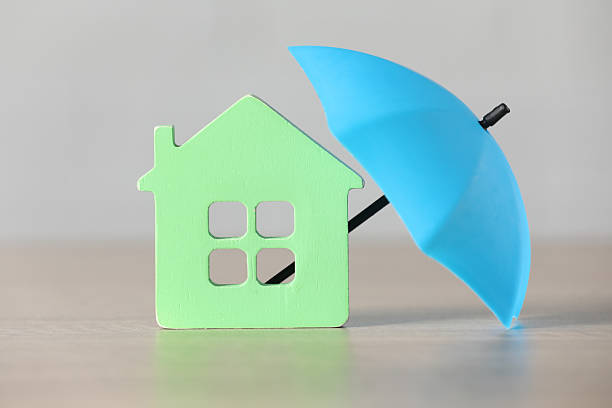 istock Property insurance. House figure and small umbrella on table 2220096616