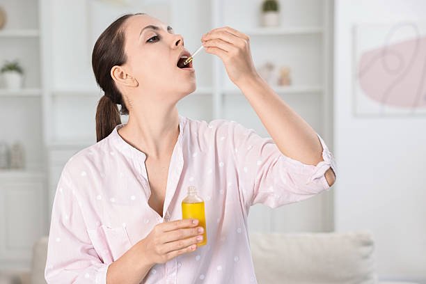 istock Young woman taking CBD tincture indoors. Herbal extract 2220096947