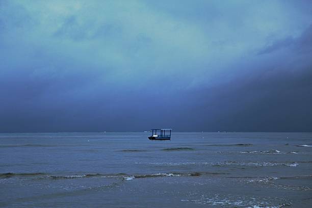 Dawn time, dark blue horizon line, calm waves on the sea, small boat parked on the shore waters