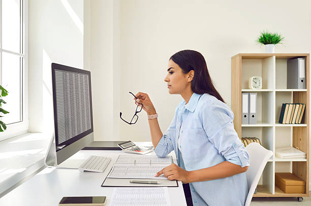 istock Confident business woman accountant working on PC computer with tables on her workplace. 2220100943