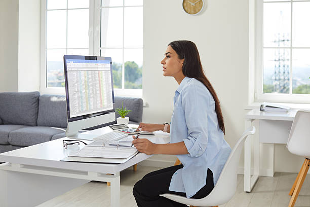 istock Confident business woman accountant working on PC computer with tables on her workplace. 2220101660