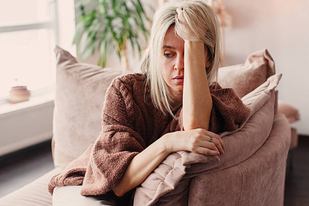 istock Frustrated Sad Woman sitting on Couch at Home 2220102045