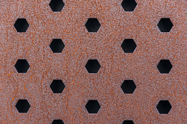 Abstract background - close-up of the grill of a construction vehicle.  Vertical columns of silver metal appear as waves.  There are uniform holes through the metal pieces for venting.