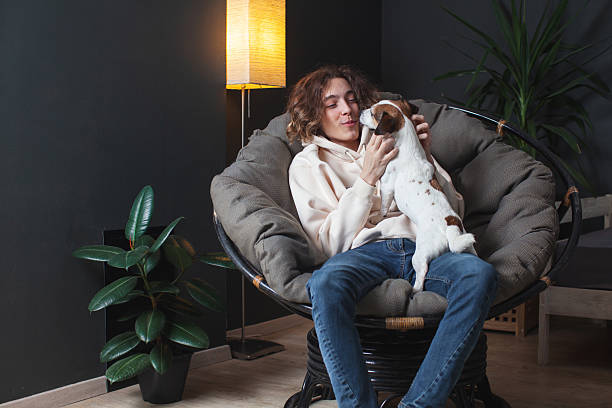 istock Man sitting on sofa with dog at home 2220106593