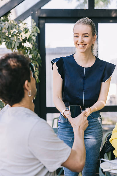 istock Smiling female waiter accepting a contactless payment from a customer 2220107344