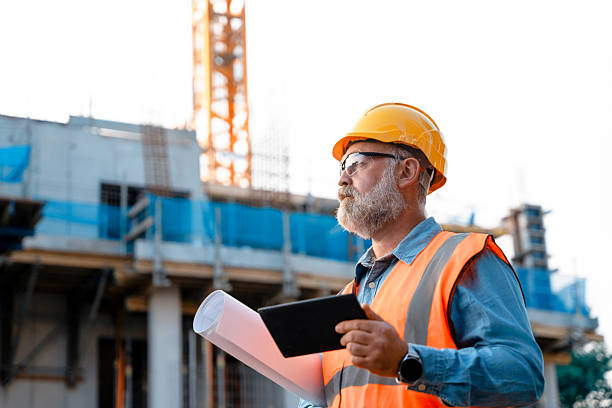 istock Construction supervisor directing workers and monitoring site progress at an urban building project with cranes and scaffolding 2220108055
