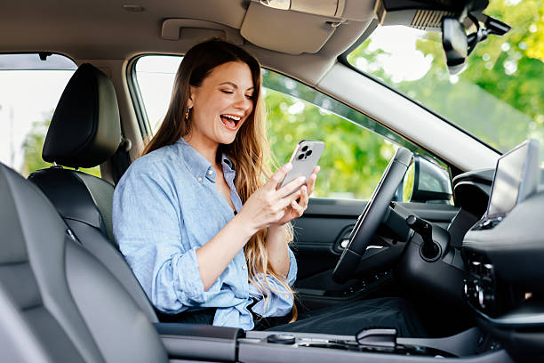 istock Cute girl driver uses cell phone in her modern car. 2220113381