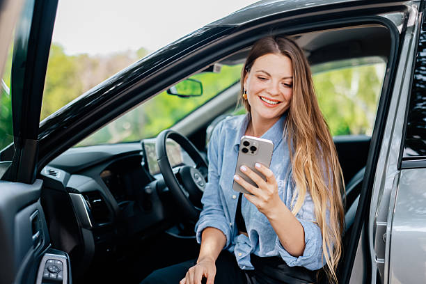 istock Cute girl driver uses cell phone in her modern car. 2220113403