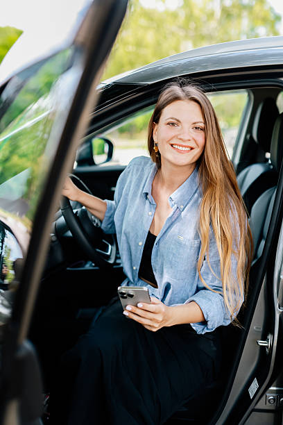 istock Cute girl driver uses cell phone in her modern car. 2220113404
