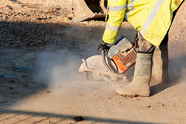 Construction worker  cutting asphalt road surface with petrol power concrete saw and diamond blade during roadworks