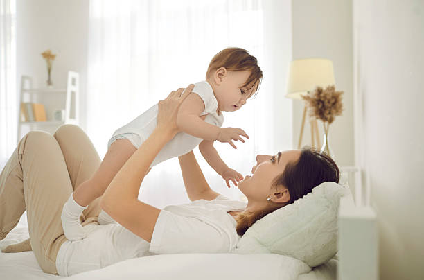 istock Caring mother relax at home playing with infant 2220115090