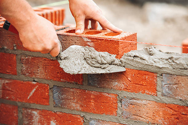 istock Close-up of Construction worker lays bricks for new structure at building site using tools and materials for masonry work 2220115181