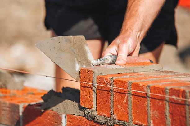 istock Close-up of Skilled worker laying bricks with trowel on construction site 2220115331