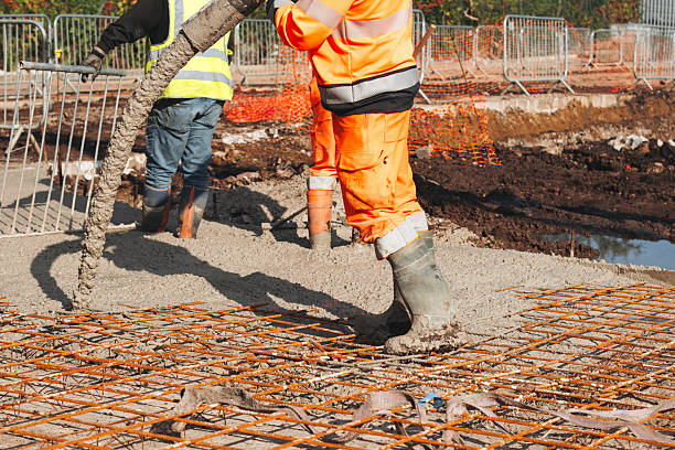 istock Construction worker pouring concrete onto reinforcing mesh at a building site 2220115933
