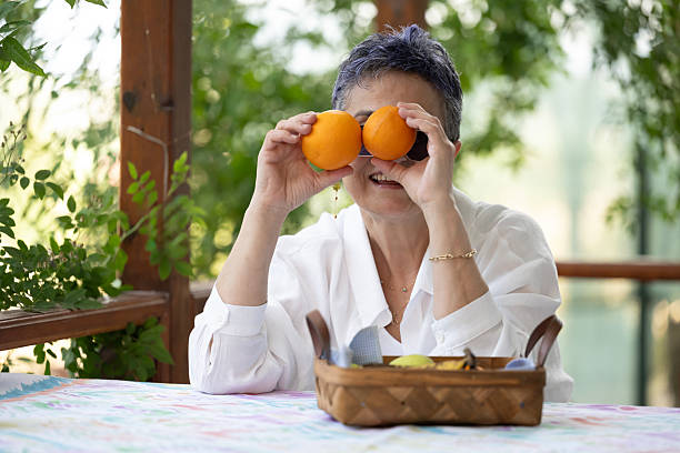 Fun old woman sitting on the balcony eating fruit