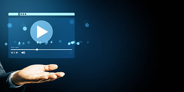 istock Business hand showing floating video player interface icon on dark blue background with bokeh light, symbolizing streaming service concept. 2220122702
