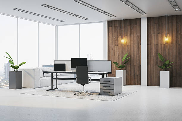 Modern executive office interior with large windows, minimalist furniture, and wood panel wall creating a bright, elegant workspace ambiance. 3D Rendering