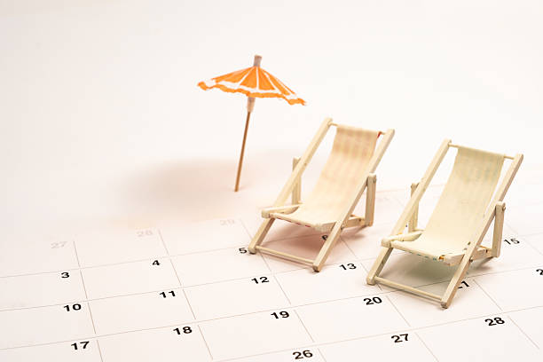 istock Planning summer vacation concept featuring miniature beach chairs and umbrella placed on a calendar page 2220122962
