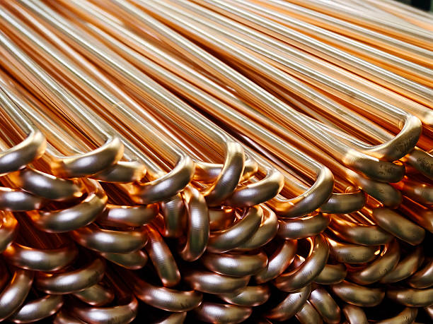 Close-up view of neatly stacked copper pipes in a manufacturing facility, showcasing their shine and smooth texture, ideal for industrial and plumbing applications.