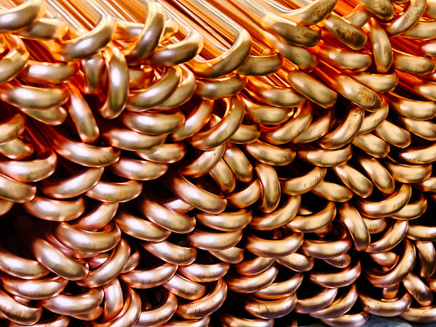 A detailed close-up image showcasing interlocking copper pipes in an industrial setting. The shiny texture and unique shapes highlight craftsmanship and material design.