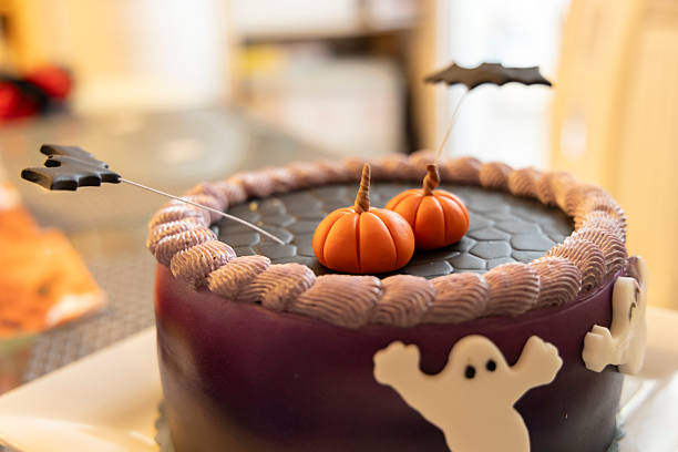 Round halloween cake with purple frosting, fondant pumpkins, bats and ghosts decorations