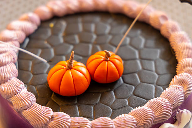 Two orange sugar pumpkins decorating a halloween cake with cobblestone pattern and purple icing