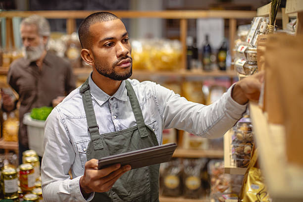 istock Professional Multiracial Grocery Worker Using Digital Tablet For Inventory Management In Specialty Food Store 2220128518