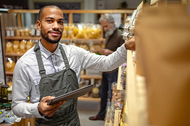 istock Professional Grocery Worker In Grey Apron Using Digital Tablet For Inventory Management 2220128522