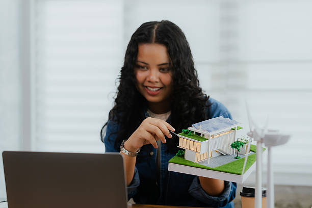 istock A smiling architect presenting a sustainable house model during a video conference or online meeting on her laptop 2220130216
