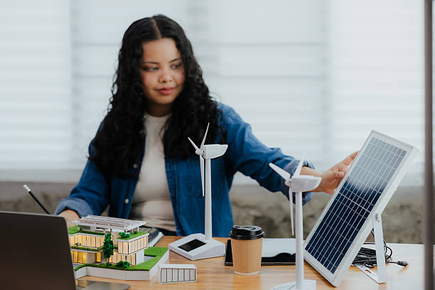 istock A female engineer working on a clean energy project, reaching to adjust a large solar panel model on her desk 2220130219