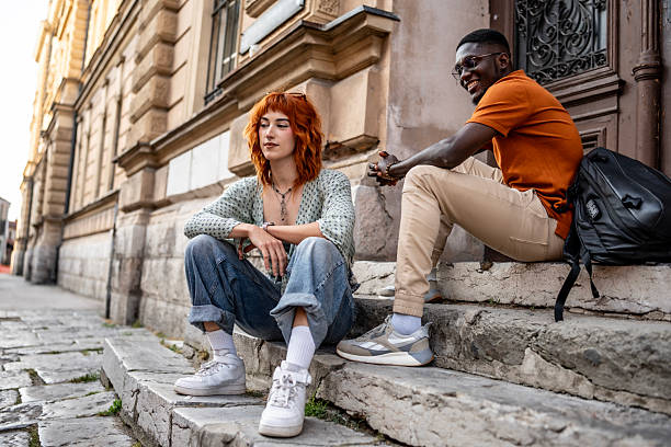 istock Young Friends Sitting on Steps Outside a Historic Stone Building 2220134171