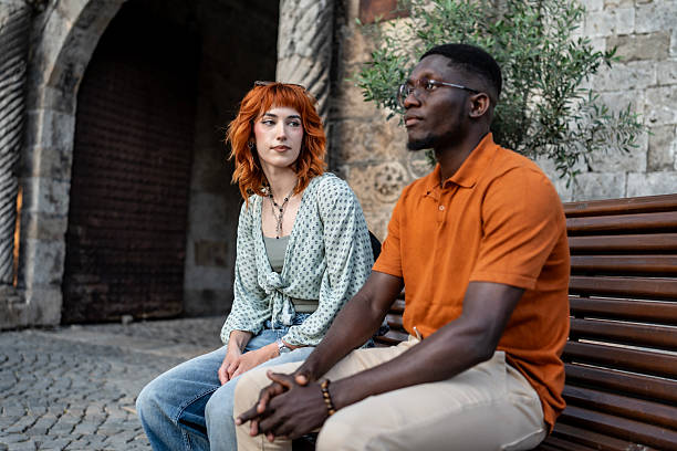 istock Two Friends Sitting and Talking on a Bench in a Historical Setting 2220134739