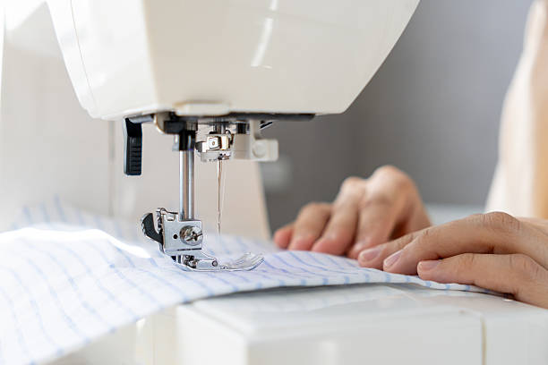 istock woman sews a light fabric on a sewing machine. making clothes, hobbies. 2220136447