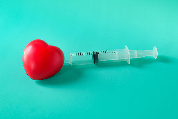 Medical syringe stuck in red heart.