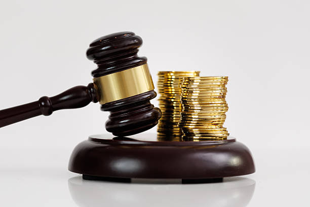 istock Judge's gavel next to stacked gold coins on a white background 2220144639
