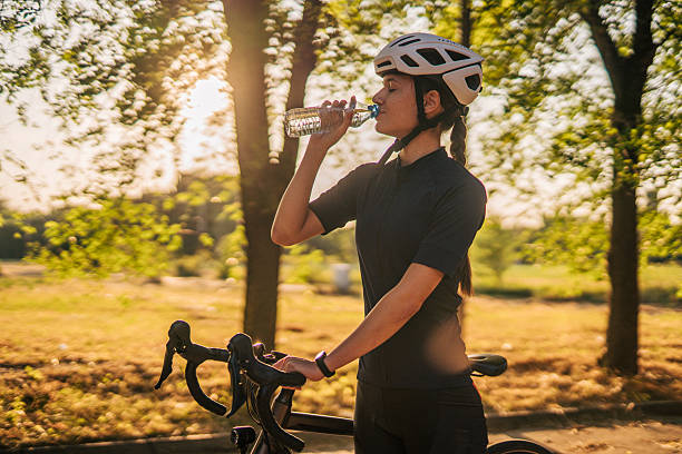 istock Female cyclist drinking water after training in a park 2220145785