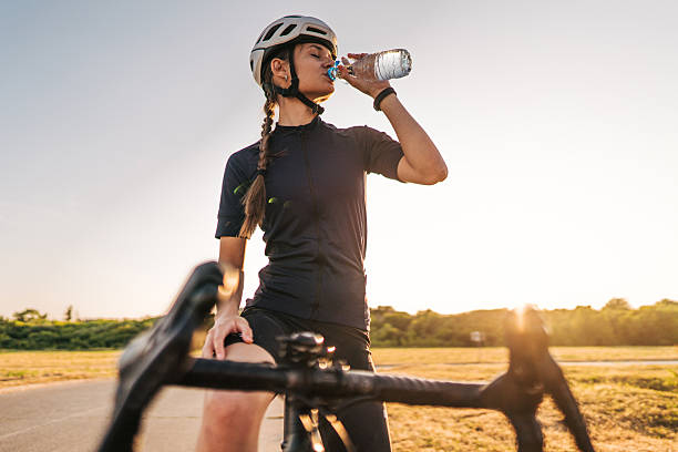istock Female cyclist drinking water during sunset bike ride 2220145824