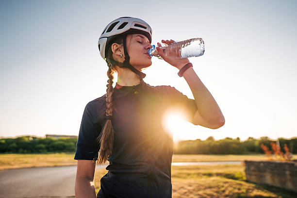 istock Female cyclist drinking water at sunset after cycling training 2220145846