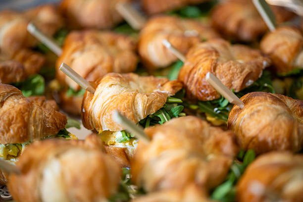 Sandwiches tramezzino filled with prosciutto and cheese, served on plate with special skewer through the middle