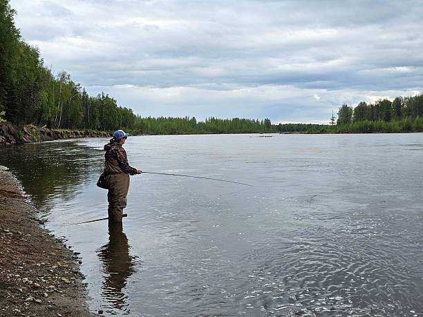 Young adult couple is fishing together on fast mountain river. Active people and sport fly fishing concept.