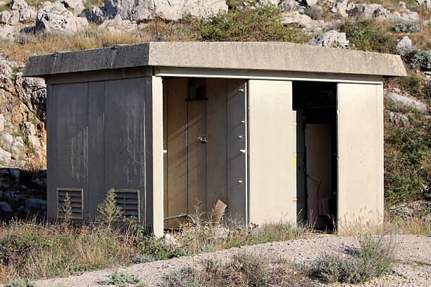 istock Concrete utility shed with open door in rocky terrain 2220150168