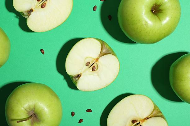 istock Flat lay composition with whole, cut apples and seeds on green background 2220151035