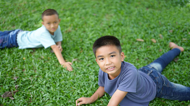 istock Two boys playing on green grass, smiling and enjoying their time outdoors. scene captures joyful moment of childhood, surrounded by nature beauty 2220153269