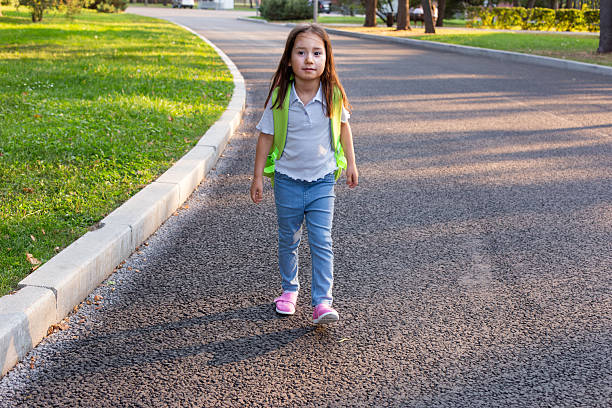 istock Young girl walking in park with backpack on sunny day 2220154503