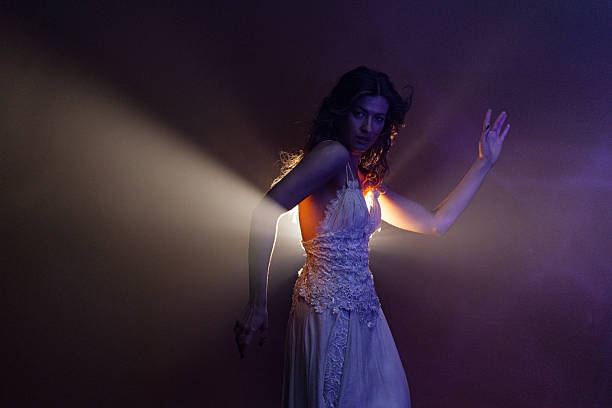 Enchanting dancer in flowing white, captured in semi-darkness with dramatic backlighting