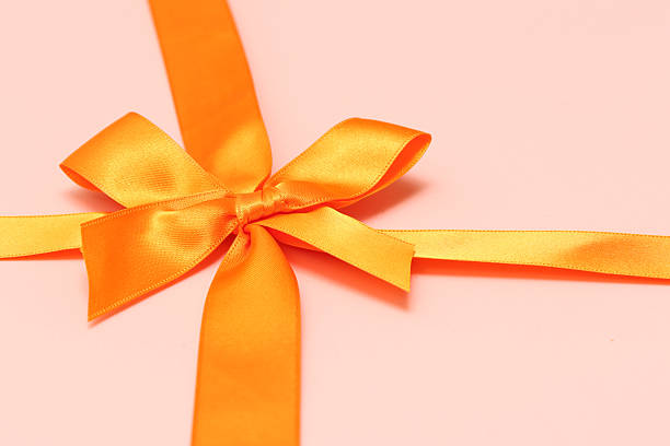 istock Orange ribbon isolated on a pink background. 2220157289